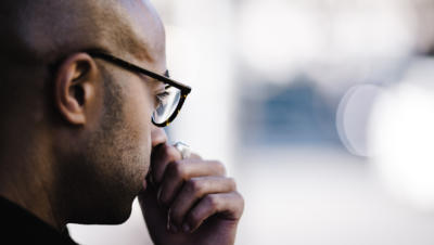 Man wearing glasses with hand up to face